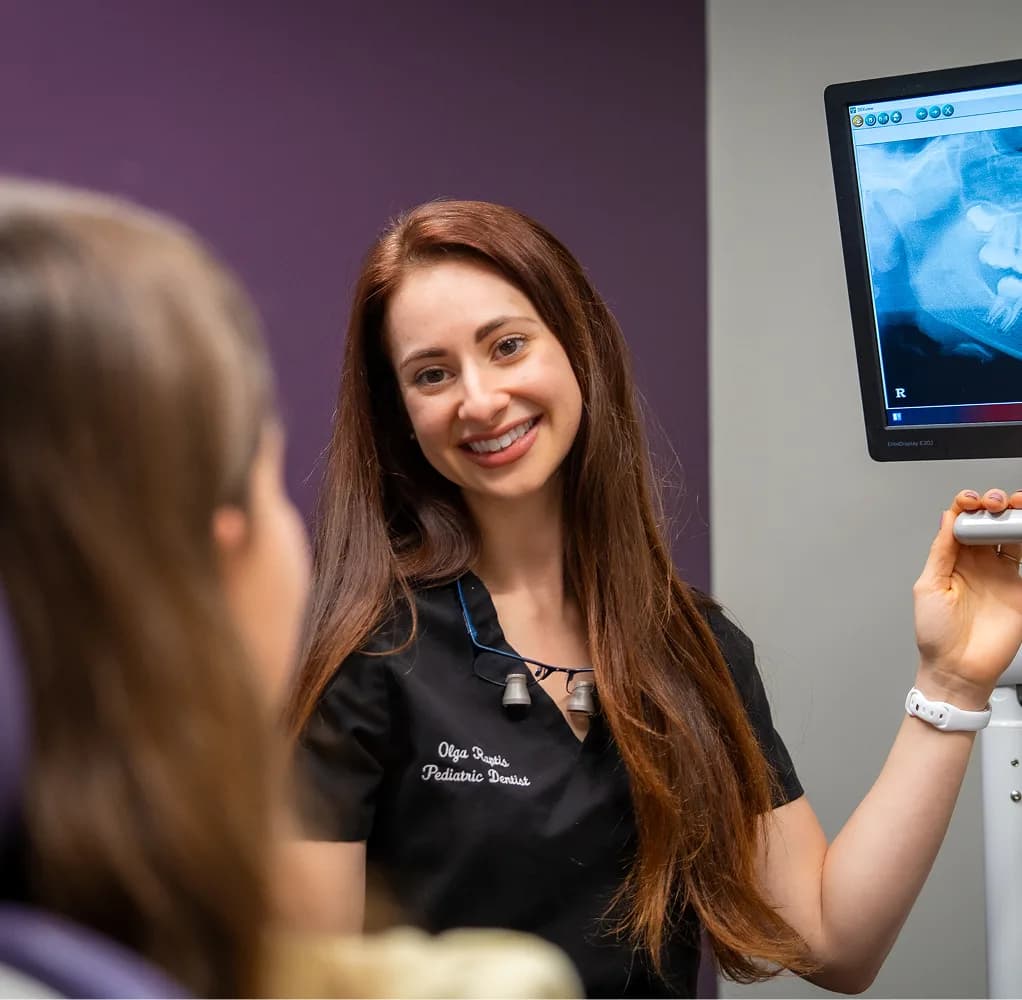 Pediatric dentist reviewing dental imaging with a patient during a consultation at Atlas Dental.